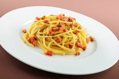 Kahverengi arka planda bir tabak spagetti carbonara.