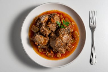 İzole Bowl 'un üst görüntüsü beyaz arka planda izole edilmiş bir parça öküzkuyruğu aşısı ve çatalla pişirilmiş.