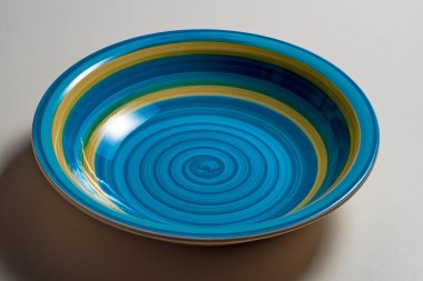 Beyaz arka planda izole edilmiş mavi fırça darbeleriyle renklendirilmiş zarif boş çorba tabağı.