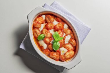 Beyaz arkaplanda Sorrento biçimi gnocchi ile seramik cocotte üst görünümü