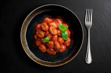 Siyah kasenin üstünde patates köftesi, fesleğen ve çatal ve siyah taş var.