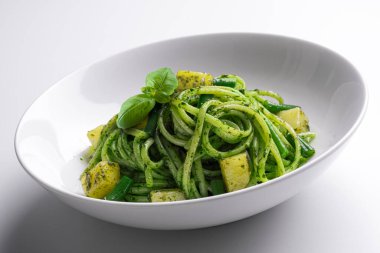 Beyaz kâse, yanında patates ve yeşil fasulye ile Ceneviz pesto soslu linguine.