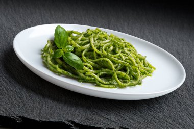 Ceneviz pesto soslu makarna ve siyah taşta fesleğen yaprağı.