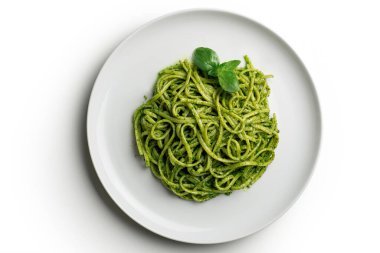 Beyaz tabağın üst görüntüsü beyaz arka planda fesleğen yapraklı Ceneviz pesto soslu linguine ile