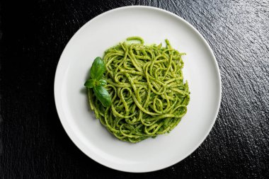 Ceneviz pesto soslu linguine ve siyah taşta fesleğen yaprağı.