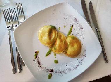 Yuvarlak ravioli ve fesleğen soslu beyaz tabağın üst görüntüsü