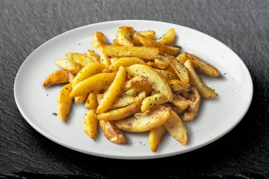 Beyaz tabak ve siyah taş kaplamalı patates kızartması.