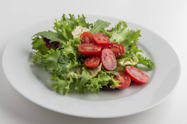 Karışık salata tabağı ve beyaz arka planda domatesler.