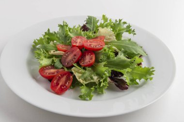 Karışık salata tabağı ve beyaz arka planda domatesler.
