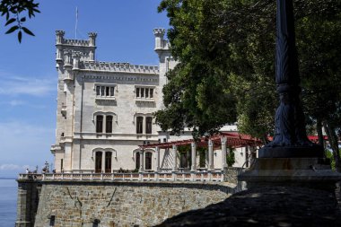 Trieste, İtalya - 7 Haziran 2023: Trieste Körfezi kıyısındaki kıyı yolundan Miramare Castle 'ın görüntüsü