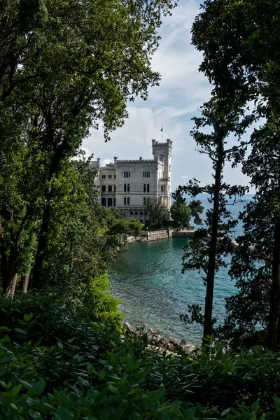Trieste, İtalya - 7 Haziran 2023: Trieste Körfezi kıyısındaki bir patikadan Miramare Kalesi 'nin manzarası