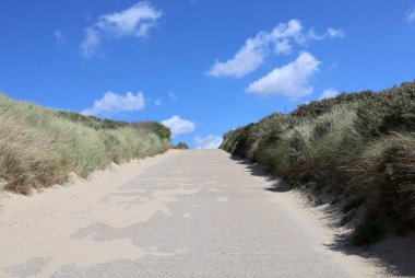 Kumullar arasında bir patika olan manzara. Mavi gökyüzü ve beyaz bulutların arkaplanı.