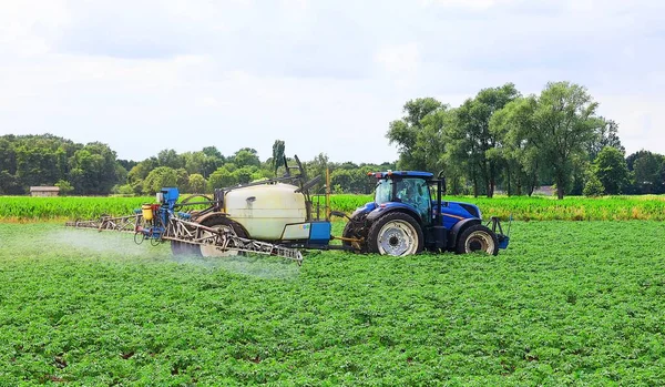 Tractor sprays crops against weeds and insects on arable land.