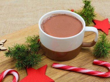 Lezzetli çikolatalı süt ve şeker kamışları kırmızı yıldızlar, çam dalları ve tahta bir tahtanın üzerinde çam kozalakları ile süslenmiş. Uzayı kopyala Noeli Kabul Et.