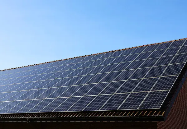  Mavi gökyüzü ve arka planda güneş ışığı olan bir çatıda güneş panelleri. Güneş enerjisi ve elektrik üretimi. Fotovoltaik paneller.