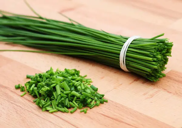  Tahta kesme tahtasındaki taze soğanlar. Bir demet ve dilimlenmiş soğan. Bahçe bitkileri.