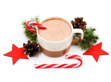 Şekerler, kırmızı yıldızlar, çam kozalakları ve çam yeşiliyle süslenmiş bir kupada ev yapımı sıcak çikolata. Beyaz arkaplanda izole edilmiş Noel kavramı.