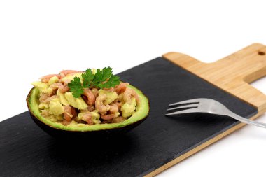 Olgun avokado ve karides. Siyah tahta üzerine lezzetli ve şenlikli aperatif beyaz arka planda izole edilmiş..