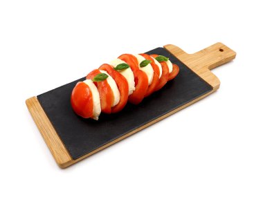 Fesleğenli domates mozzarella beyaz arka planda izole edilmiş bir levhada servis edilir. Lezzetli aperatif..