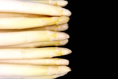 Siyah arka planda beyaz kuşkonmaz. Üst görünümde kopyalama alanı olan bir grup kuşkonmaz.