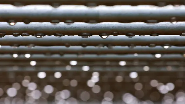  Yatay çubuklara yağmur damlaları. Seçici odaklanma. Su damlaları ve bokeh ile soyut arkaplan.