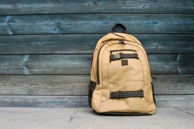 Ahşap bir arka plana karşı bir sırt çantası. Okul konsepti. Boşluğu kopyala.