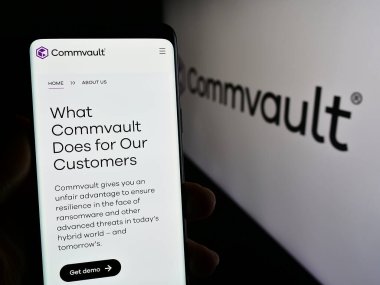 Stuttgart, Almanya - 04-26-2024: ABD 'li yazılım şirketi Commvault Systems Inc.' in web sayfası ile logo önünde akıllı telefon tutan kişi. Telefon ekranının merkezine odaklan.