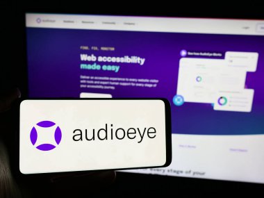 Stuttgart, Almanya - 04-26-2024: Amerikan yazılım şirketi AudioEye Inc. 'in logosuna sahip cep telefonu sahibi kişi iş sayfasının önünde. Telefon ekranına odaklan.