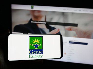 Stuttgart, Almanya - 04-26-2024: İnternet sitesi önünde üzerinde ABD 'li petrol ve gaz şirketi Genie Energy Ltd.' nin logosu bulunan akıllı telefon sahibi kişi. Telefon ekranına odaklan.
