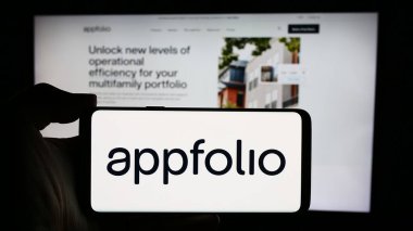 Stuttgart, Almanya - 04-28-2024: ABD 'li emlak yazılım şirketi AppFolio Inc.' in logosuyla cep telefonu sahibi kişi iş sayfasının önünde. Telefon ekranına odaklan.