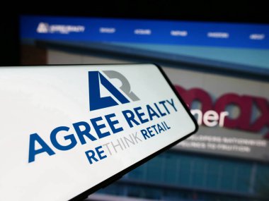 Stuttgart, Almanya - 04-28-2024: Web sitesi önünde üzerinde Amerikan emlak şirketi Agree Realty Corporation logosu bulunan cep telefonu. Telefon ekranının merkez soluna odaklan.