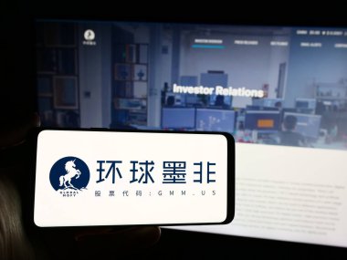 Stuttgart, Almanya - 04-28-2024: Çinli Global Mofy Metaverse Limited şirketinin logosuna sahip akıllı telefon sahibi kişi web sitesinin önünde. Telefon ekranına odaklan.