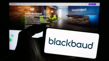 Stuttgart, Almanya - 04-28-2024: Web sitesi önünde üzerinde ABD 'li yazılım şirketi Blackbaud Inc.' in logosu olan akıllı telefon sahibi kişi. Telefon ekranına odaklan.