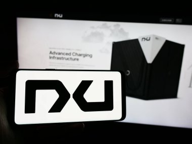 Stuttgart, Almanya - 04-28-2024: İnternet sitesi önünde ABD 'li pil teknoloji şirketi Nxu Inc.' in logosuna sahip kişi. Telefon ekranına odaklan.