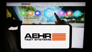 Stuttgart, Almanya - 04-28-2024: ABD 'li yarı iletken test şirketi Aehr Test Systems' in logosuna sahip cep telefonu sahibi kişi iş sayfası önünde. Telefon ekranına odaklan.