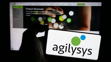 Stuttgart, Almanya - 04-28-2024: Web sitesi önünde ABD 'li yazılım şirketi Agilysys Inc.' in logosuna sahip kişi. Telefon ekranına odaklan.