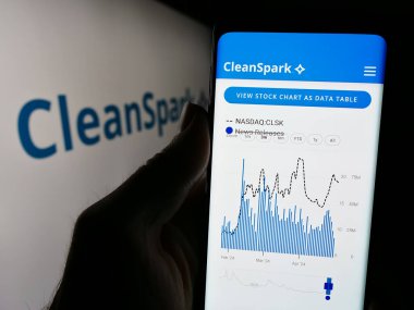 Stuttgart, Almanya - 04-28-2024: ABD 'li Bitcoin maden şirketi CleanSpark Inc.' in internet sitesi ile iş logosu önünde cep telefonu bulunduran kişi. Telefon ekranının merkezine odaklan.