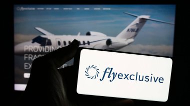 Stuttgart, Almanya - 04-29-2024: ABD 'li özel jet şirketinin özel jet uçuşu logosuna sahip akıllı telefon sahibi kişi web sitesinin önünde. Telefon ekranına odaklan.