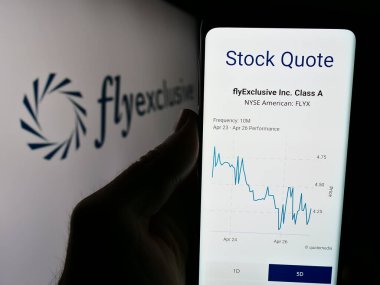 Stuttgart, Almanya - 04-29-2024: ABD 'li özel jet şirketinin özel uçuşu ile ilgili web sitesi olan akıllı telefon sahibi kişi iş logosu önünde. Telefon ekranının merkezine odaklan.