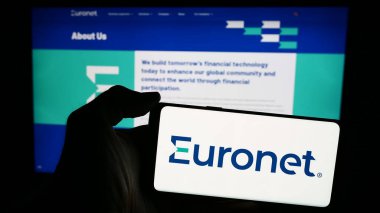 Stuttgart, Almanya - 04-29-2024: Amerikan ödeme şirketi Euronet Worldwide Inc. 'in logosuyla cep telefonu sahibi kişi iş sayfasının önünde. Telefon ekranına odaklan.