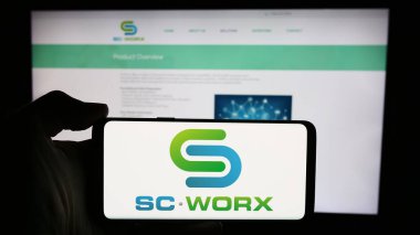 Stuttgart, Almanya - 04-29-2024: ABD sağlık tedarik zinciri SCWorx Corp 'un logosuna sahip cep telefonu sahibi kişi iş sayfasının önünde. Telefon ekranına odaklan.
