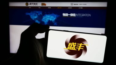 Stuttgart, Almanya - 04-29-2024: Çinli lojistik şirketi Shengfeng Development Ltd. 'nin logosuna sahip akıllı telefon sahibi kişi web sitesi önünde. Telefon ekranına odaklan.