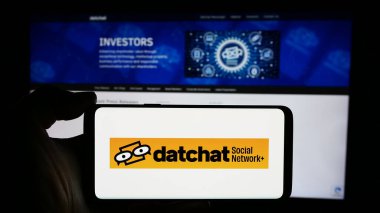 Stuttgart, Almanya - 05-02-2024: ABD 'li metaevren ve sosyal medya şirketi DatChat Inc.' in logosuyla cep telefonu sahibi kişi iş sayfası önünde. Telefon ekranına odaklan.