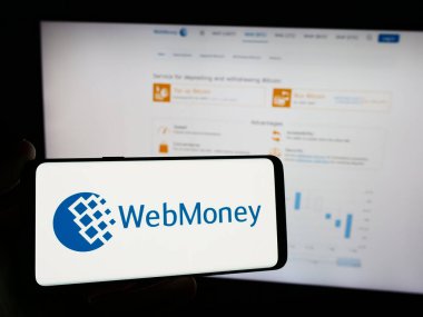 Stuttgart, Almanya - 05-03-2024: İnternet sitesi önünde Rus çevrimiçi ödeme şirketi WebMoney Transfer 'in logosuna sahip kişi. Telefon ekranına odaklan.