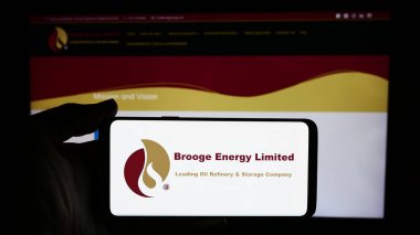 Stuttgart, Almanya - 05-06-2024: Emirati petrol şirketi Brooge Energy Limited 'in logosunun bulunduğu cep telefonu sahibi kişi iş sayfasının önünde. Telefon ekranına odaklan.