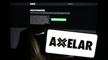 Stuttgart, Almanya - 05-07-2024: İnternet sayfası önünde ağ geliştirme şirketi Axelar Foundation 'ın logosuyla cep telefonu tutan kişi. Telefon ekranına odaklan.