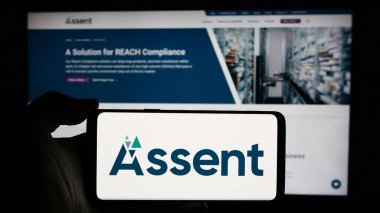 Stuttgart, Almanya - 05-08-2024: Kanada tedarik zinciri şirketi Assent Compliance Inc. 'in logosunun bulunduğu cep telefonu sahibi kişi iş sayfasının önünde. Telefon ekranına odaklan.