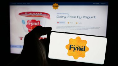 Stuttgart, Almanya - 05-14-2024: ABD 'li şirket The Fynder Group Inc. (Doğa Fynd)' in web sayfası ile logo önünde cep telefonu bulunduran kişi. Telefon ekranının merkezine odaklan.