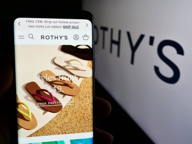 Stuttgart, Almanya - 05-14-2024: ABD 'li ayakkabı ve aksesuar şirketi Rothy' s Inc. 'in web sayfası logonun önünde cep telefonu tutan kişi. Telefon ekranının merkezine odaklan.
