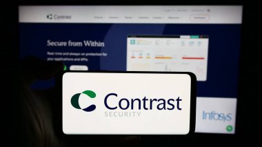 Stuttgart, Almanya - 05-14-2024: ABD 'li yazılım şirketi Contrast Security Inc.' in logosuyla cep telefonu sahibi kişi iş sayfasının önünde. Telefon ekranına odaklan.